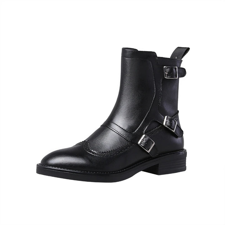 Black leather Chelsea boot with buckle straps and brogue toe cap, studio shot