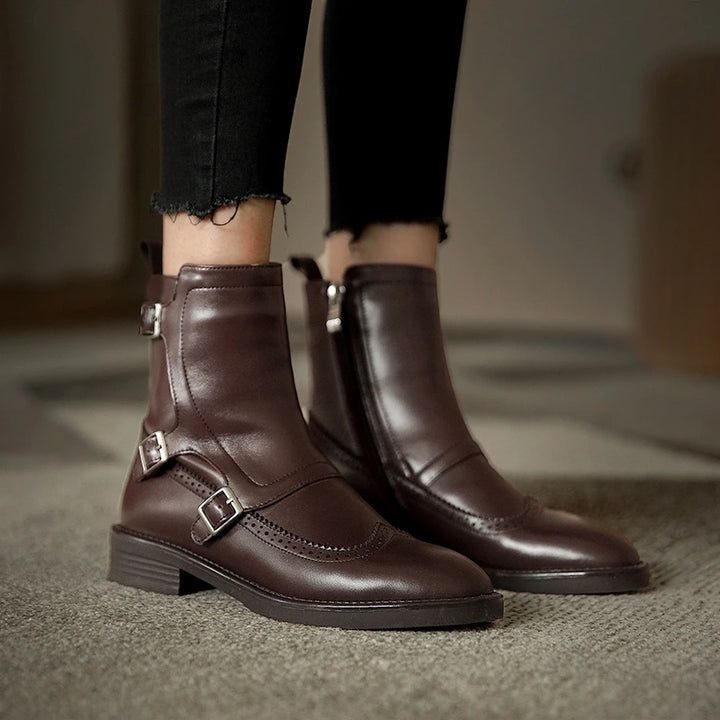 Woman wearing pair of brown leather Chelsea boots with buckle straps, front view