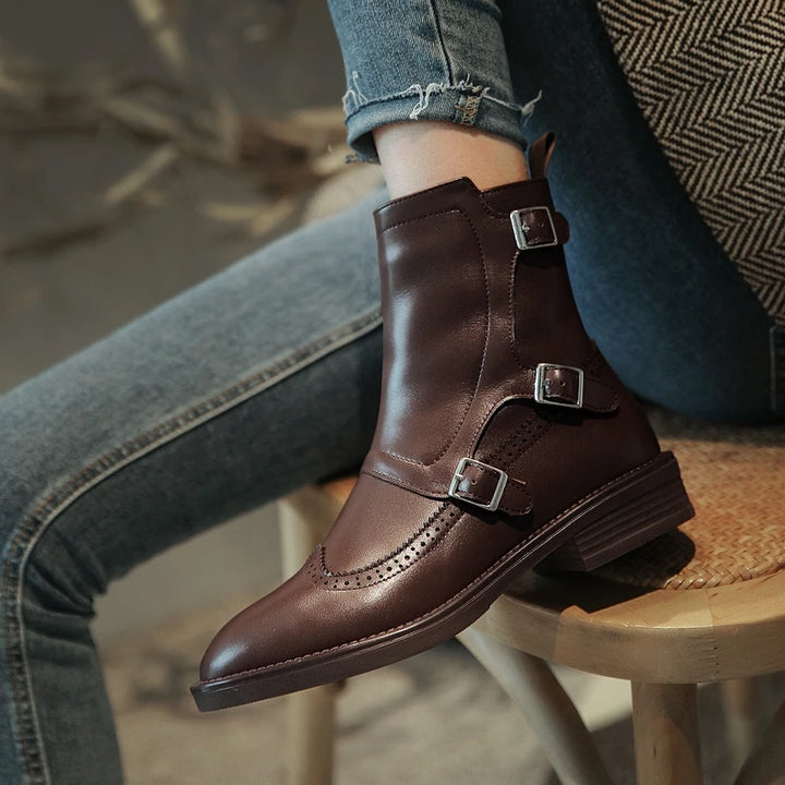 Woman wearing brown leather Chelsea boot with triple buckle straps, side view