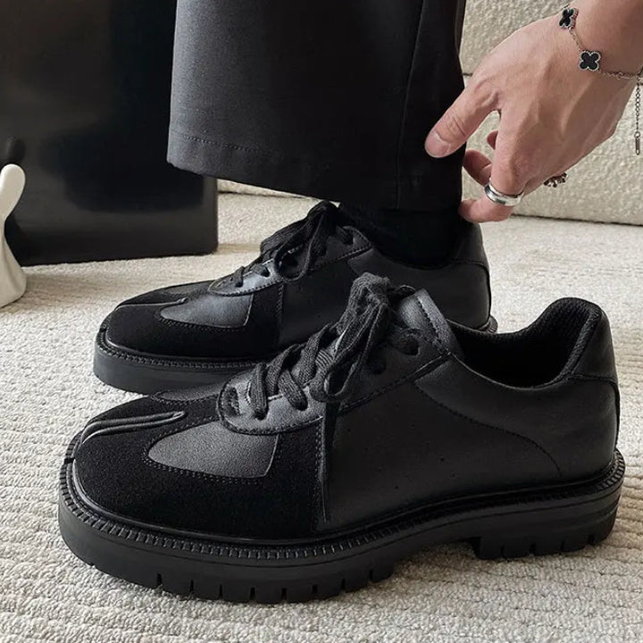 Man wearing black Tabi sneakers with tailored trousers, side view