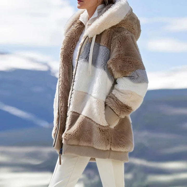 Woman wearing tan colorblock fleece hooded jacket with mountain backdrop