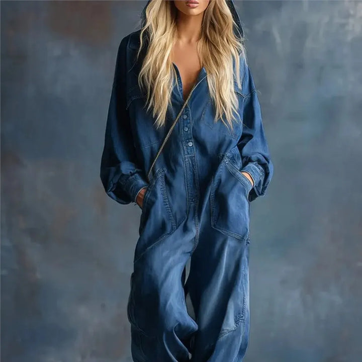 Woman wearing deep blue hooded denim jumpsuit with hands in pockets