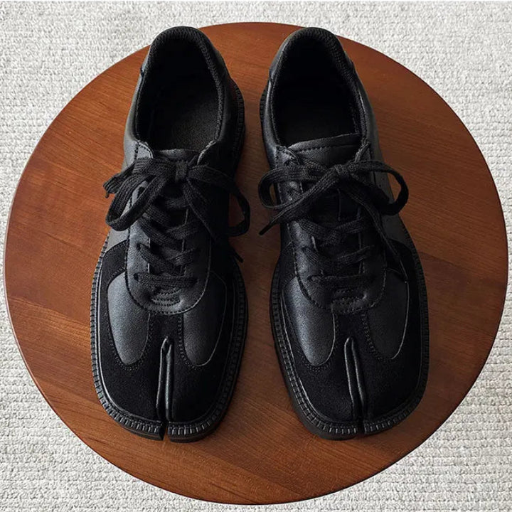 Top down view of black Tabi sneakers on wood table