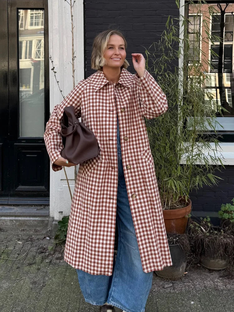 Woman wearing red and white gingham trench coat over jeans