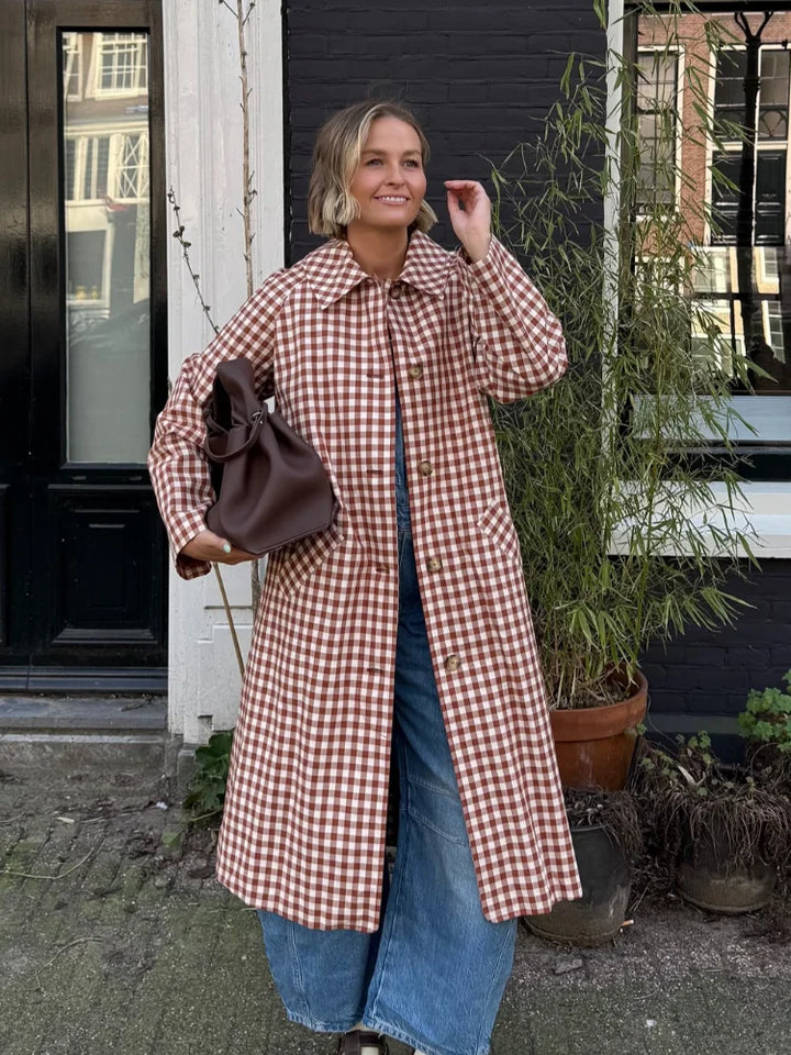 Woman wearing red and white gingham trench coat over jeans