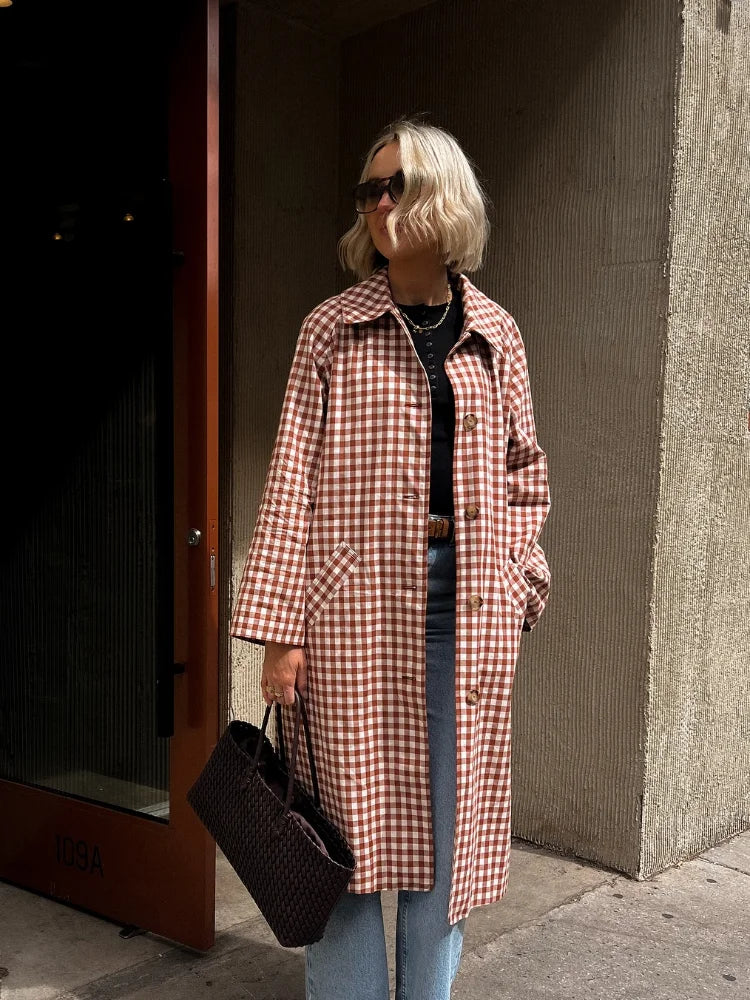 Gingham trench coat worn open over black top and jeans