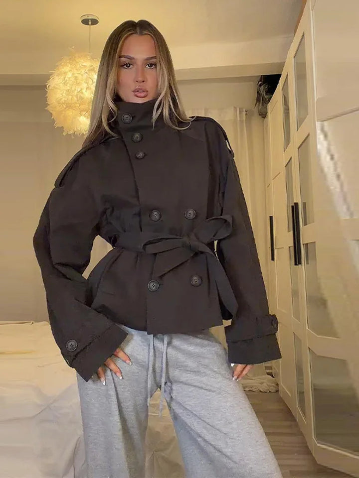 Woman wearing black double breasted trench coat with stand collar and tie belt