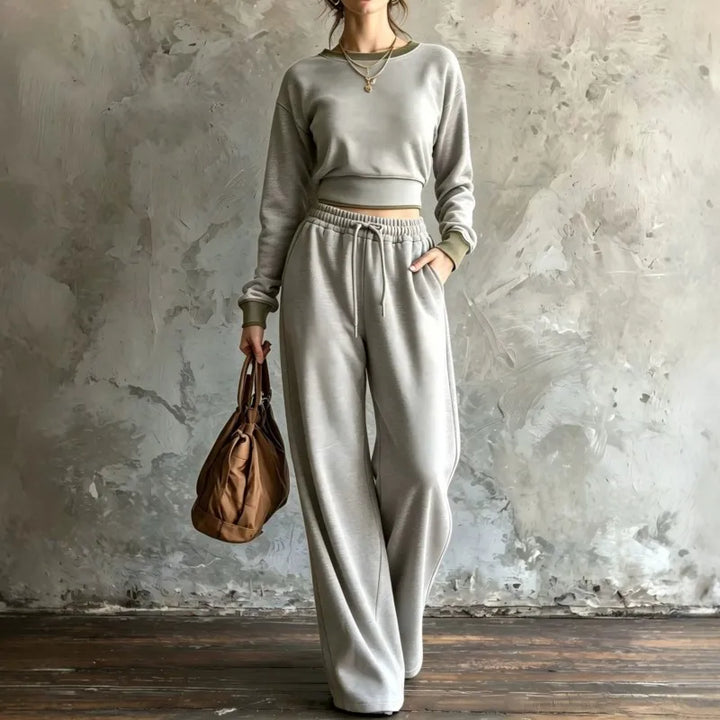 Woman wearing light grey cropped sweatshirt and wide leg pants set with olive trim
