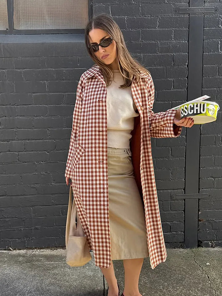 Model in gingham trench coat with cream sweater and skirt