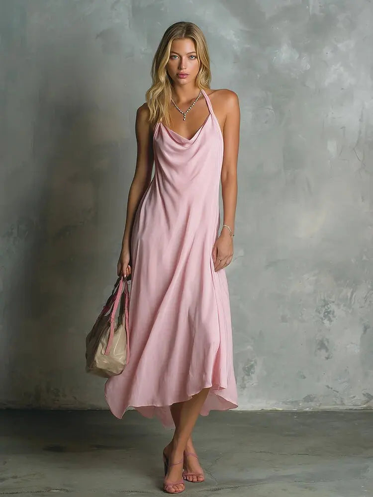 Woman in pink cowl neck halter midi dress standing against textured wall