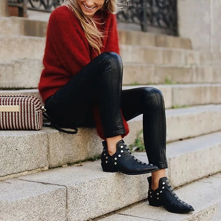 Woman wearing black studded ankle boots sitting on steps