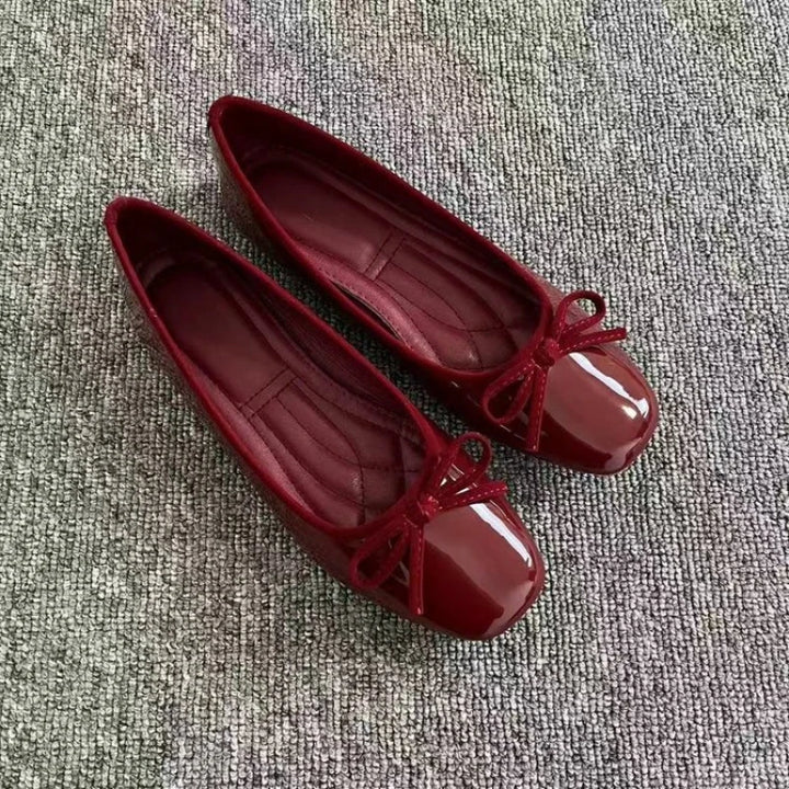 Red patent ballet flats with bow detail, angled view