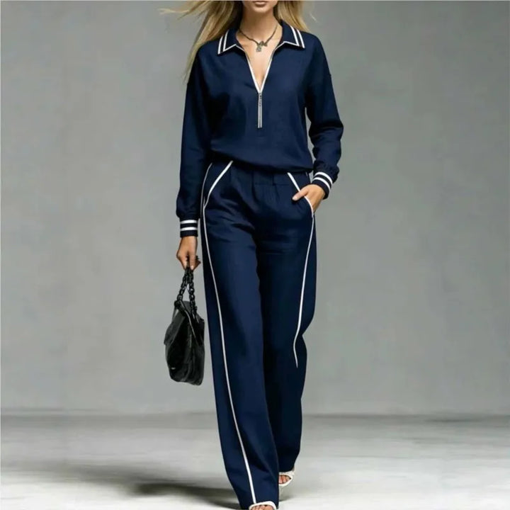Woman wearing deep blue half-zip two piece pant set with contrast stripe trim