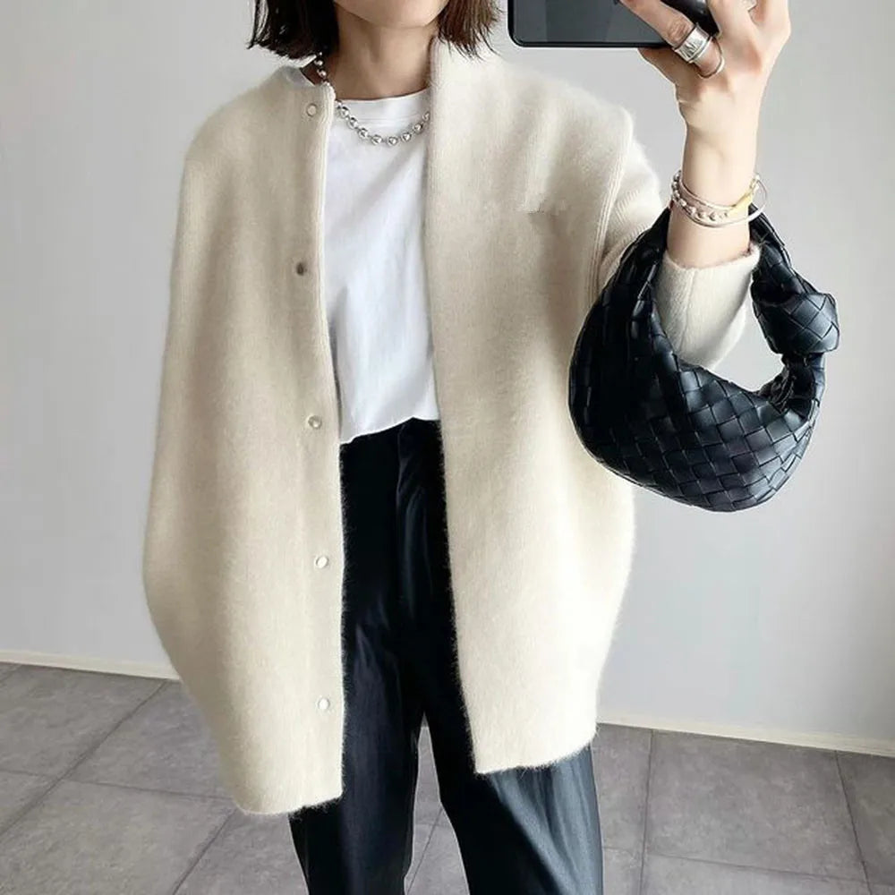 Off-white knit cardigan with collarless neckline styled with black pants