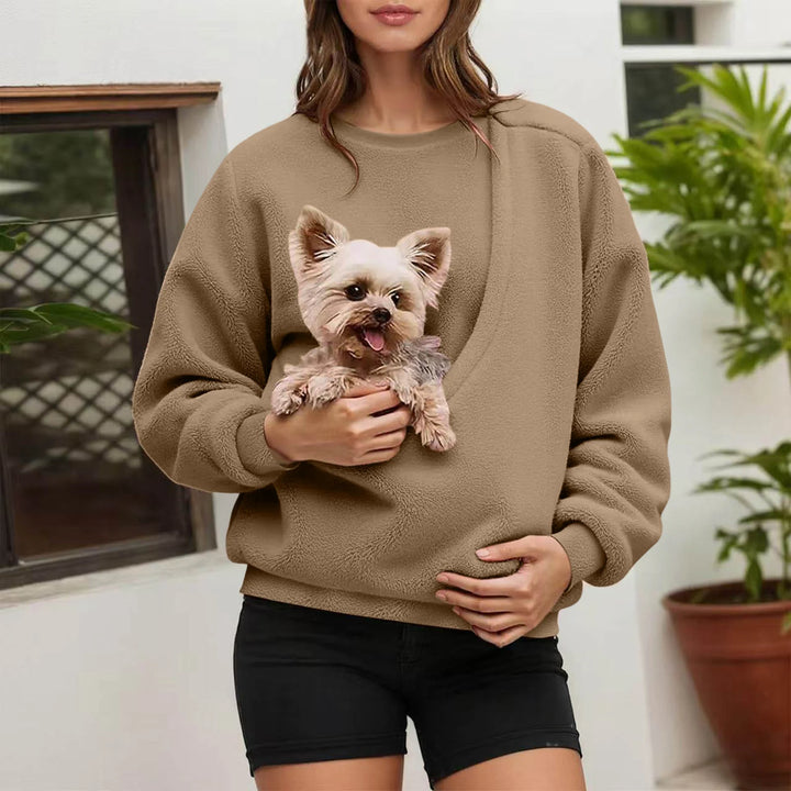 Woman holding small dog in beige fleece pullover pocket outdoors