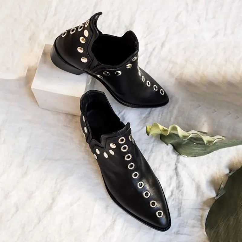 Pair of black leather grommet ankle boots on fabric backdrop