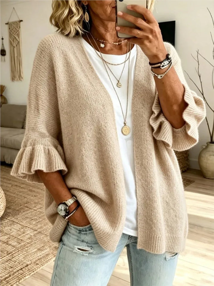 Woman wearing beige knit cardigan with ruffle sleeves, open front view