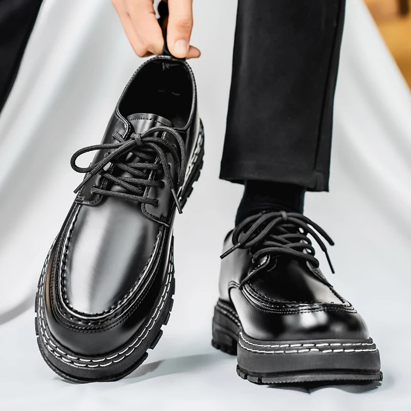 Man holding black leather derby shoe while wearing the other on foot