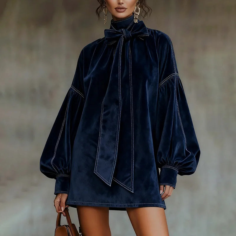 Woman wearing navy velvet mini dress with bow tie collar and lantern sleeves, front view close up