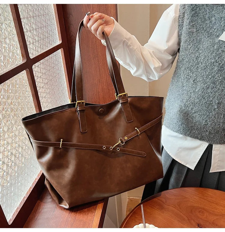 Light brown leather tote bag held on wooden table
