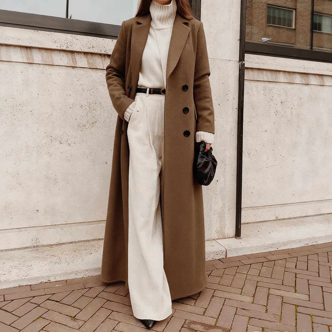 Woman wearing brown long trench coat over cream sweater and pants