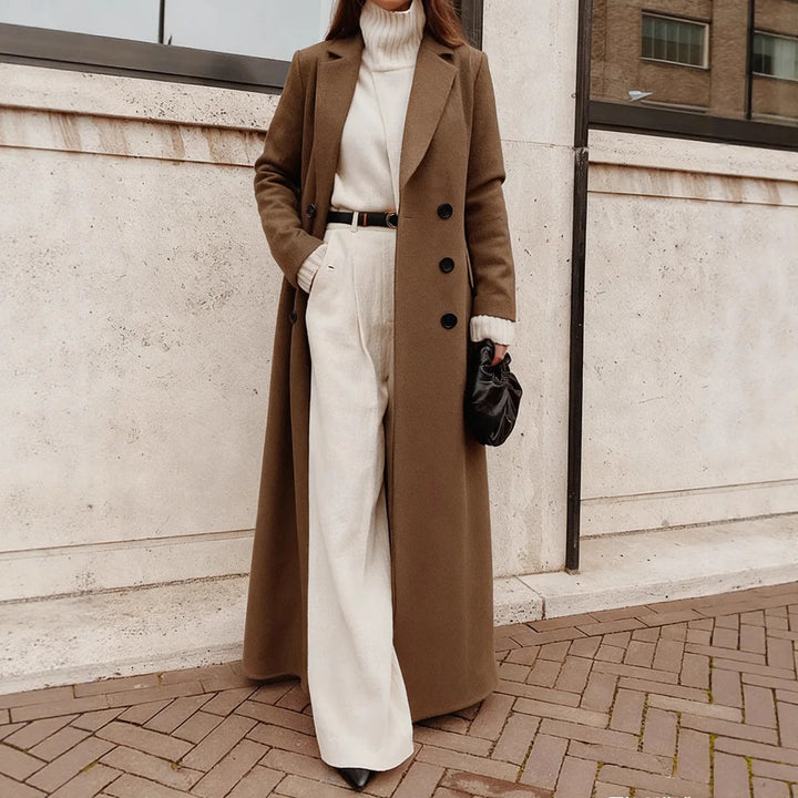 Woman wearing brown long trench coat over cream sweater and pants