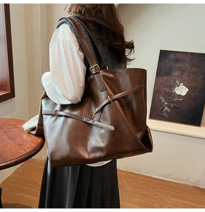 Woman wearing light brown leather tote bag on shoulder