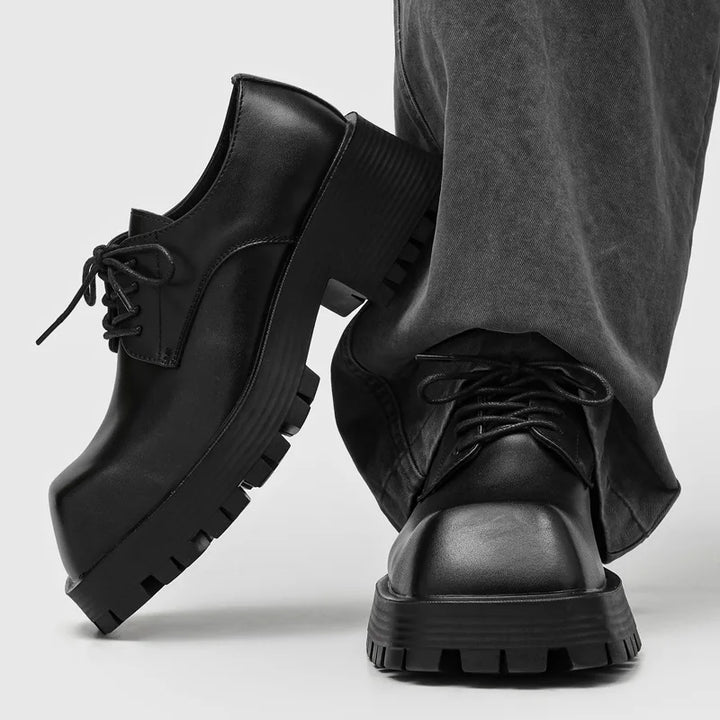 Black leather derby shoes with chunky lug sole shown crossed