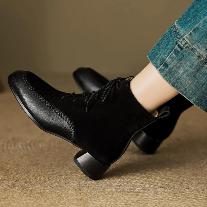 Black suede lace-up ankle boots worn with denim trousers