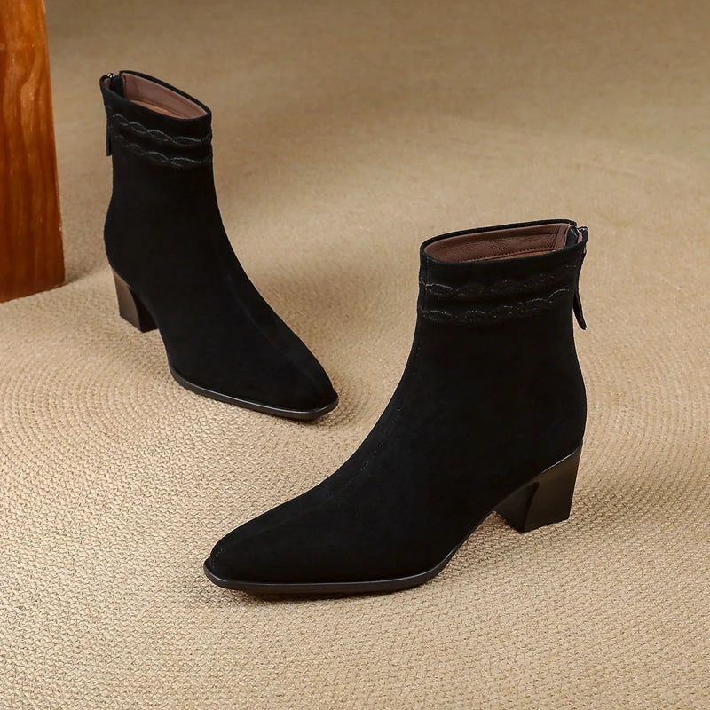 Pair of black suede ankle boots on carpet floor