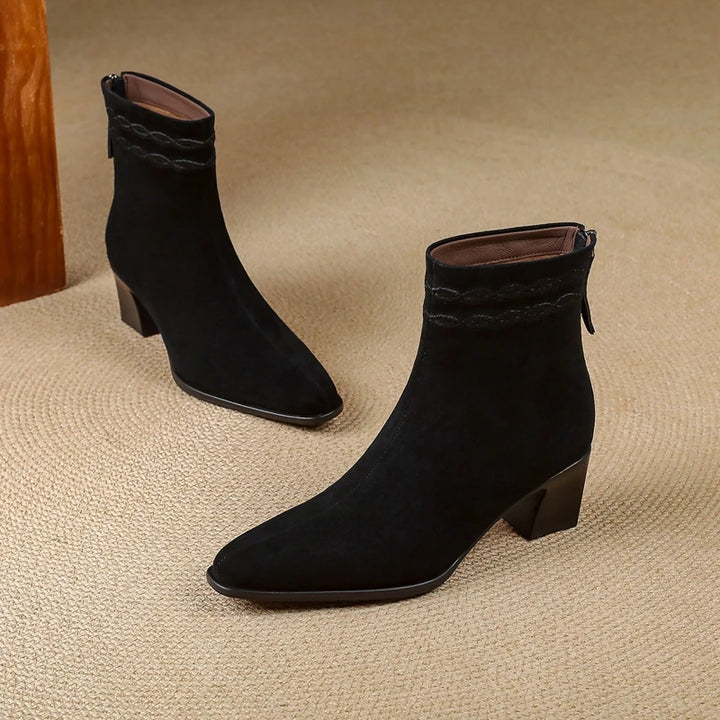 Pair of black suede ankle boots on carpet floor