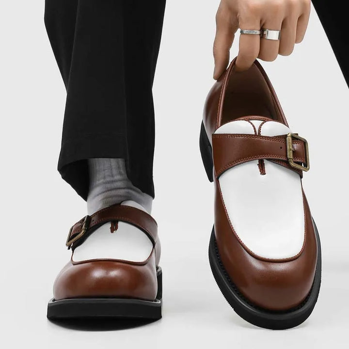 Man holding brown and white two-tone loafer showing buckle and sole detail