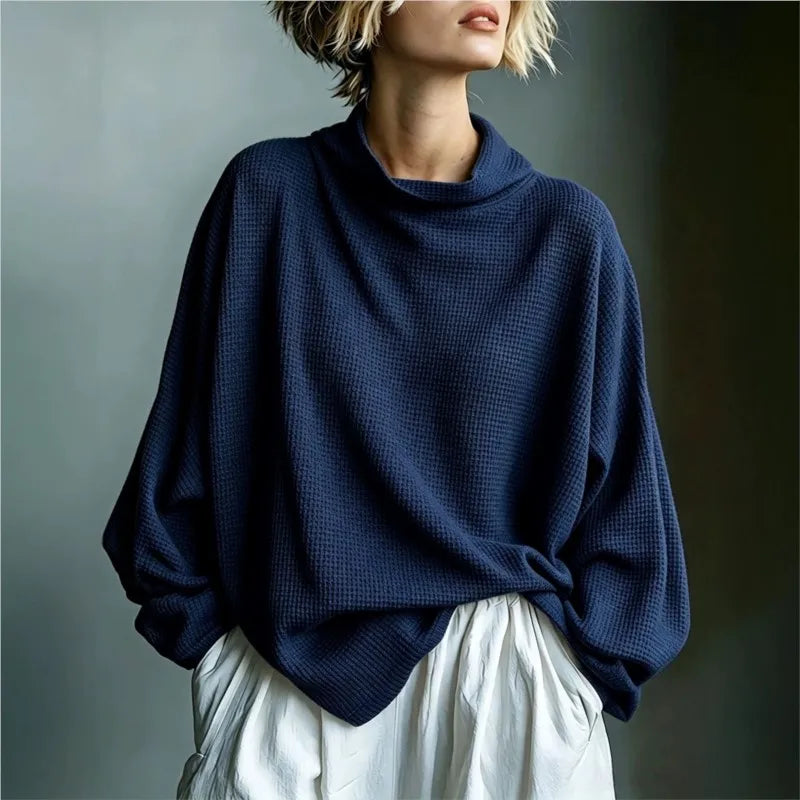Woman wearing navy blue waffle knit top with funnel collar, front view