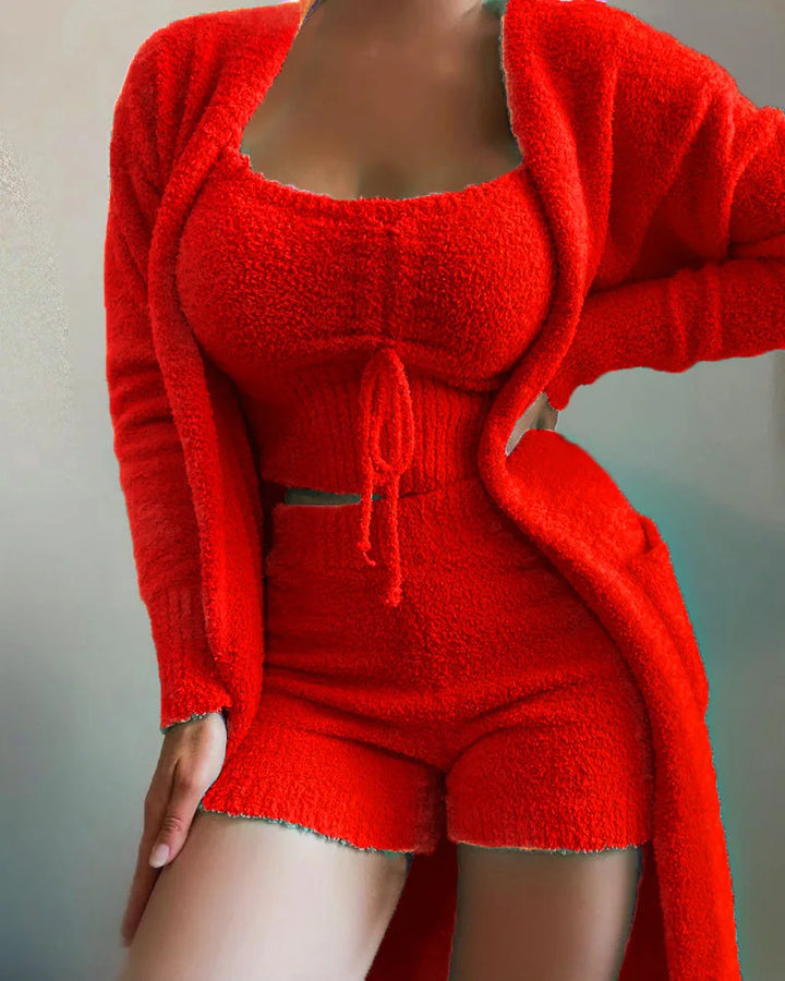 Woman wearing red three piece bouclé knit loungewear set with cardigan, vest and shorts