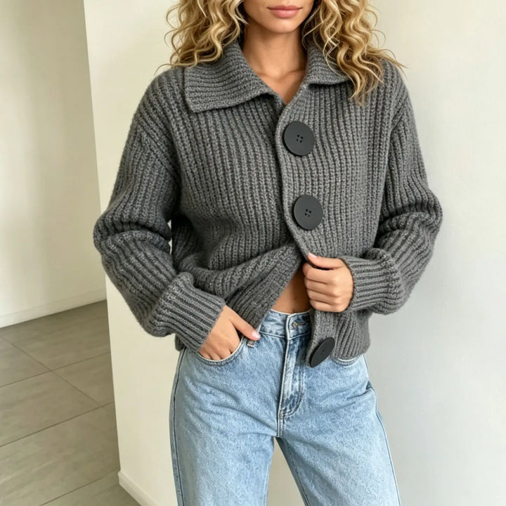 Woman wearing grey ribbed knit cardigan with statement buttons, hands in pockets