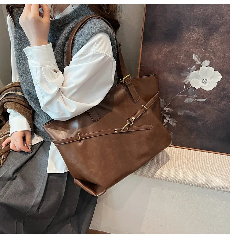 Woman carrying light brown leather tote bag near painting