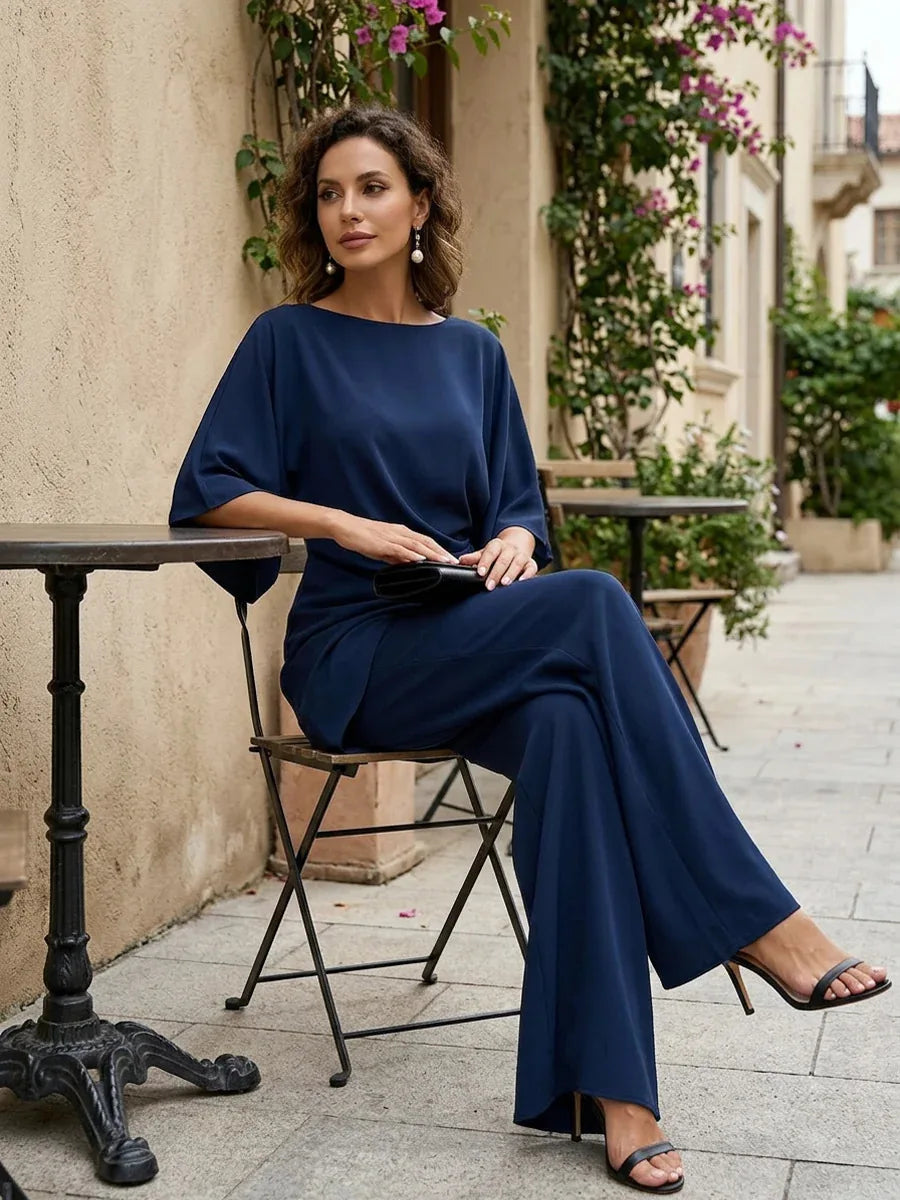 Navy blue two piece set styled with wide leg pants, seated pose