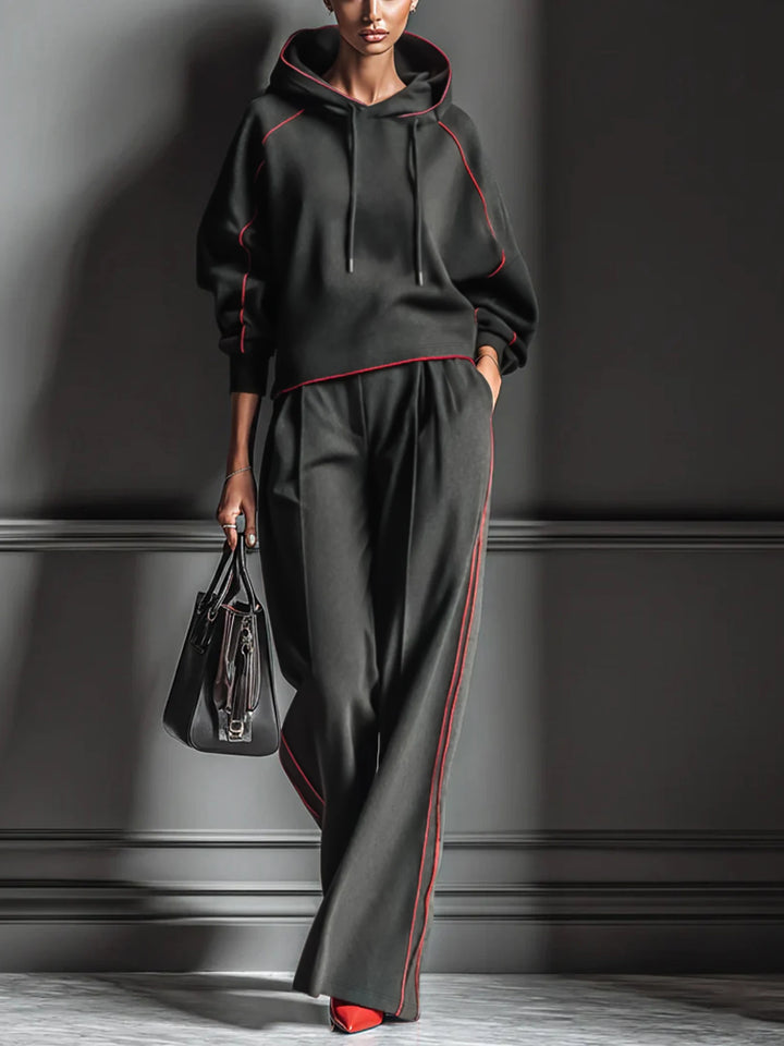 Woman wearing black hoodie and wide leg pants set with red piping, front view