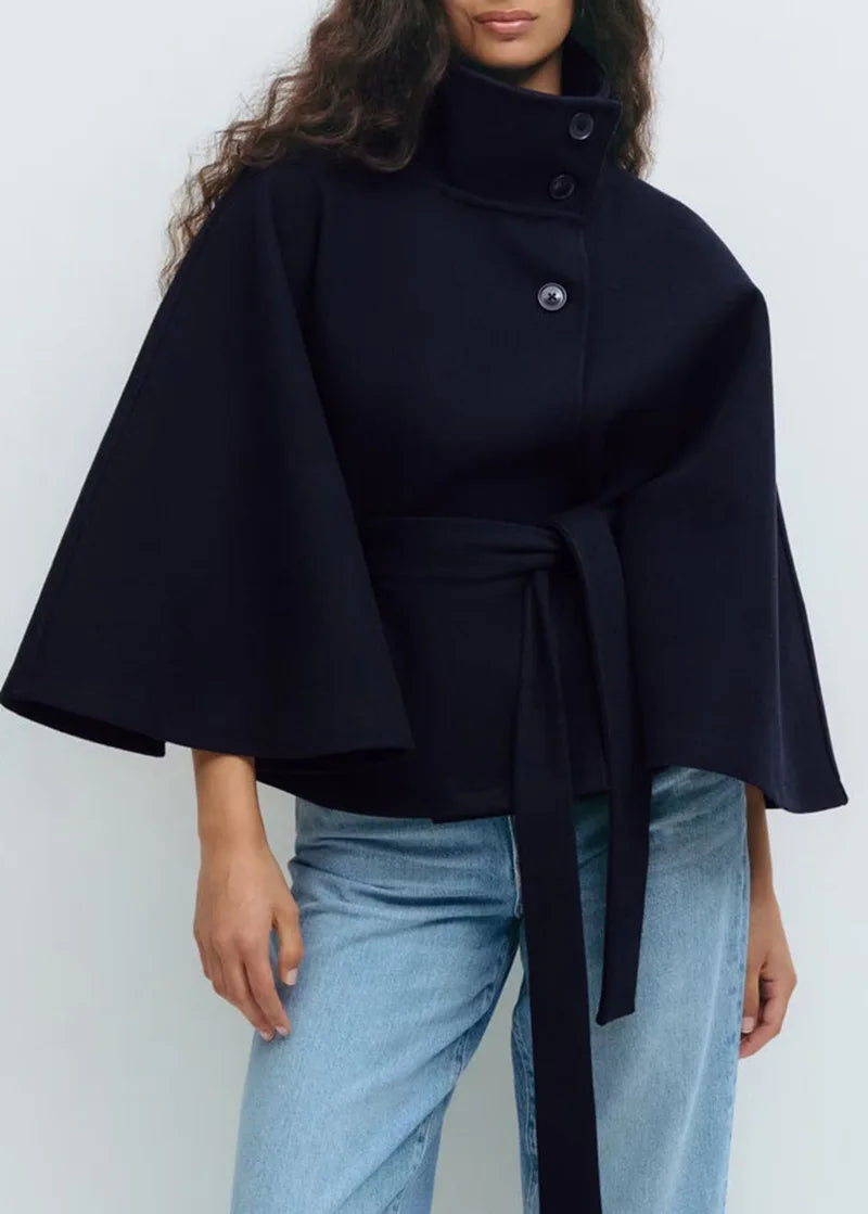 Woman wearing navy cape jacket with belted waist, front view
