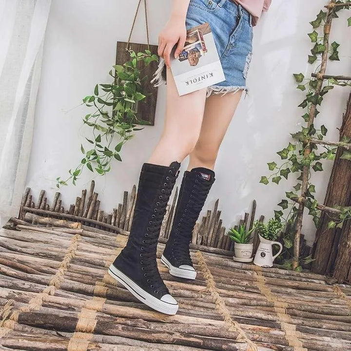 Model wearing black knee-high lace-up canvas boots outdoors