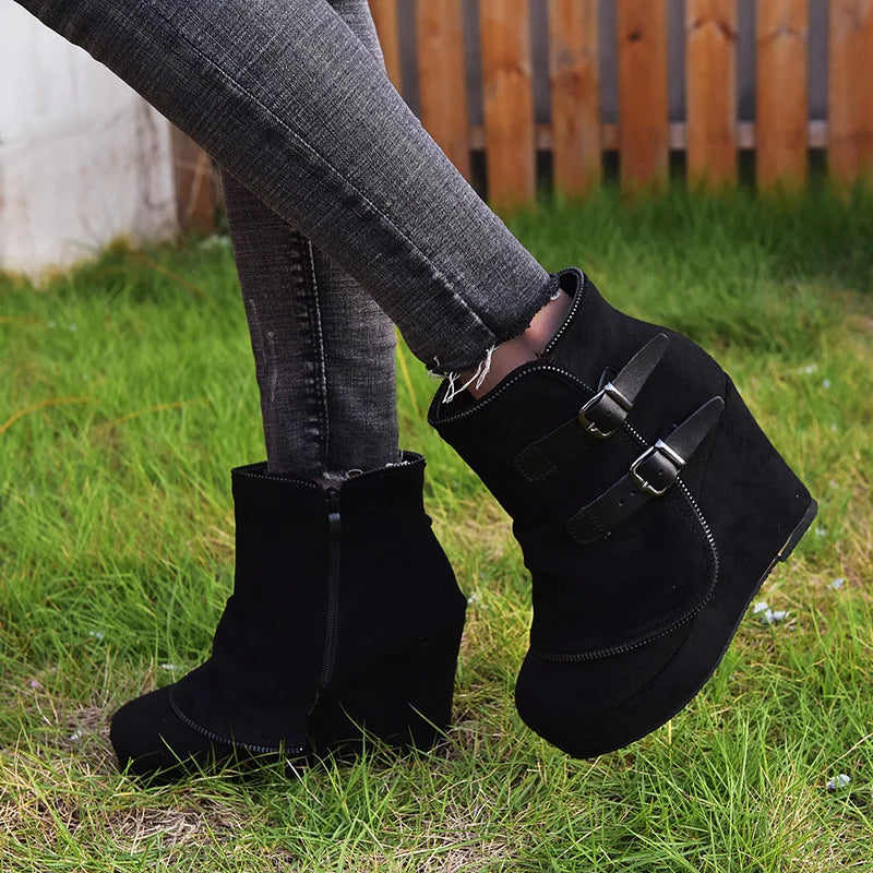Model wearing black suede wedge ankle boots on grass