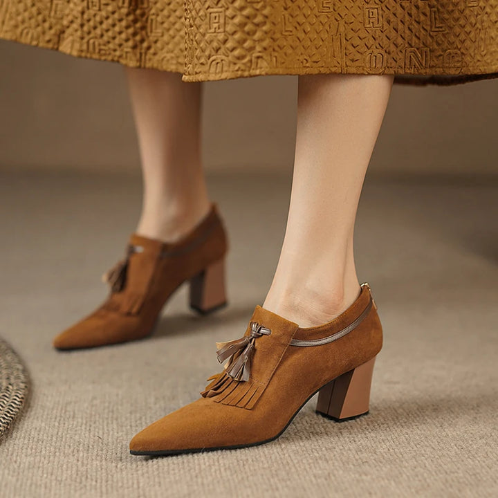 Side view of brown suede pump on model's foot with skirt