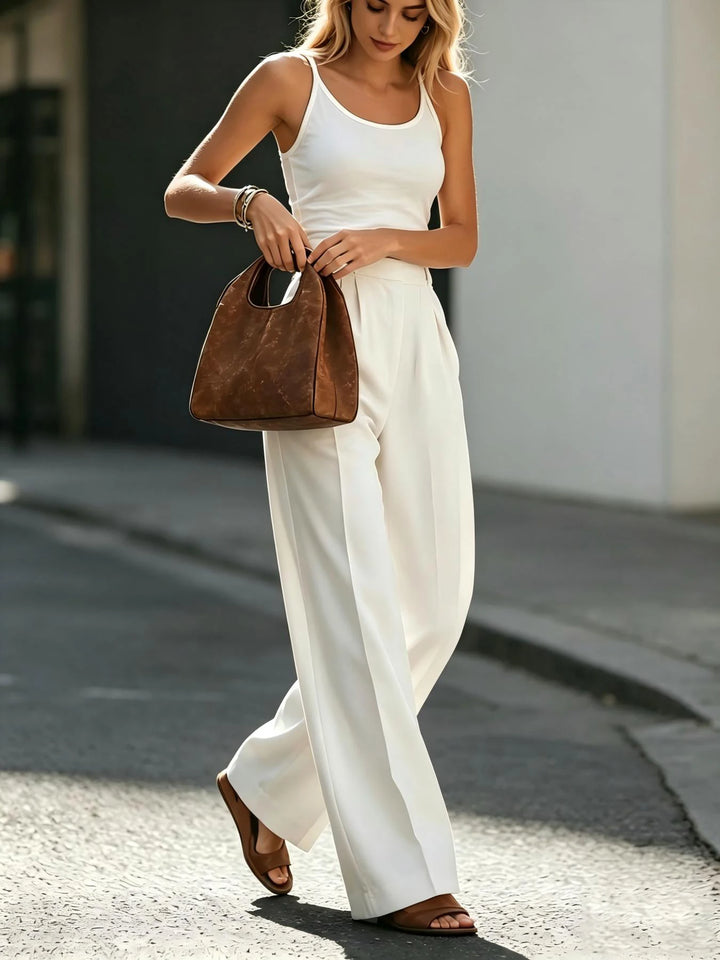 Woman wearing white wide leg pleated trousers with belt, front view