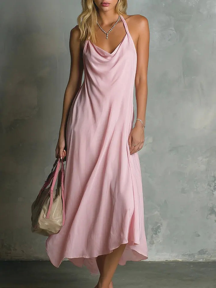 Woman in pink cowl neck halter midi dress holding a handbag, front view