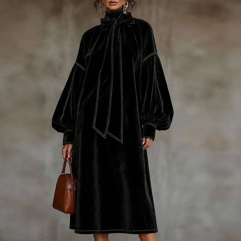 Woman wearing black velvet maxi dress with bow tie neckline