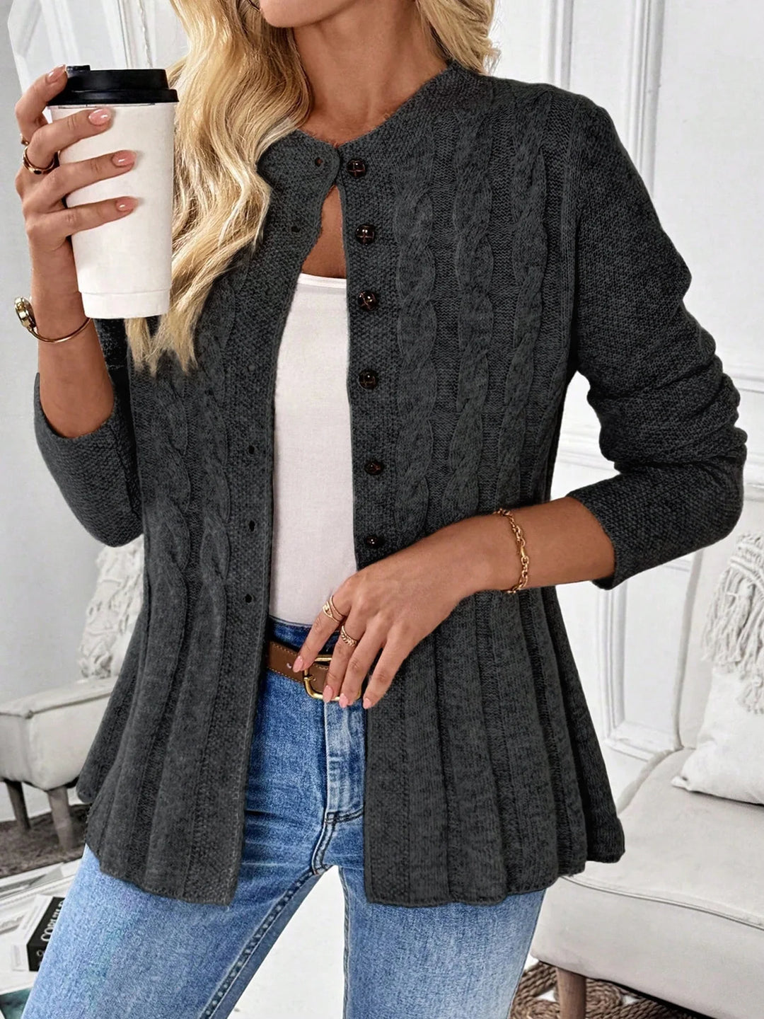 Woman wearing dark gray cable knit peplum cardigan holding coffee cup