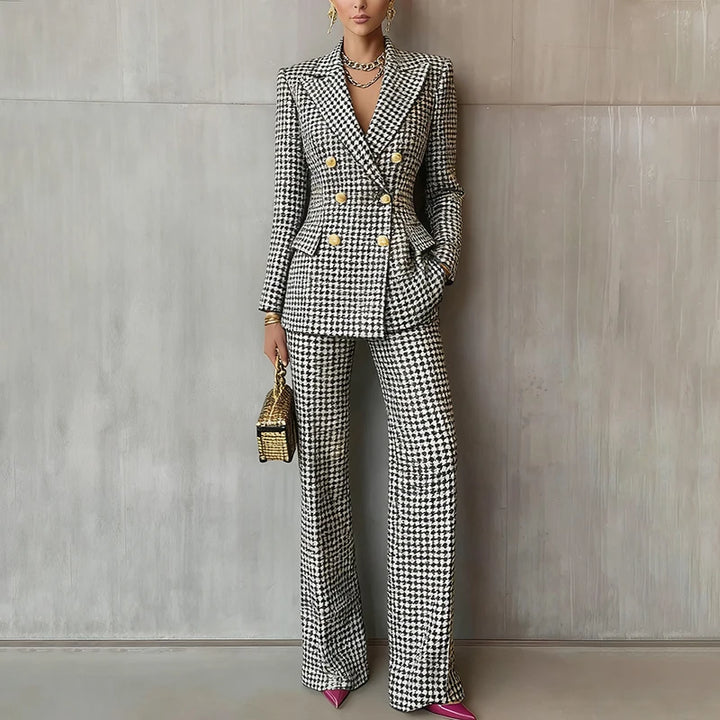 Close view of black and white houndstooth blazer and trouser suit against concrete wall
