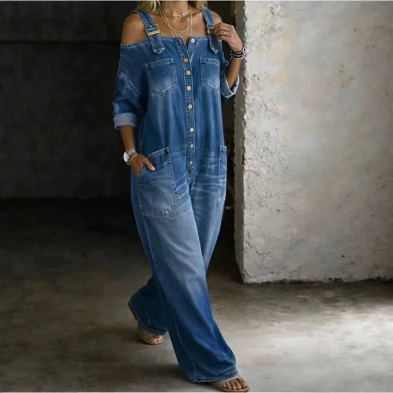 Woman wearing blue denim cold shoulder jumpsuit against wall