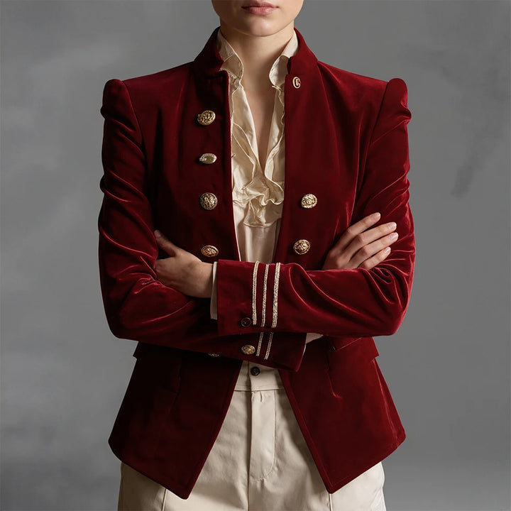 Close up of burgundy velvet blazer with gold buttons and braided cuffs, arms crossed