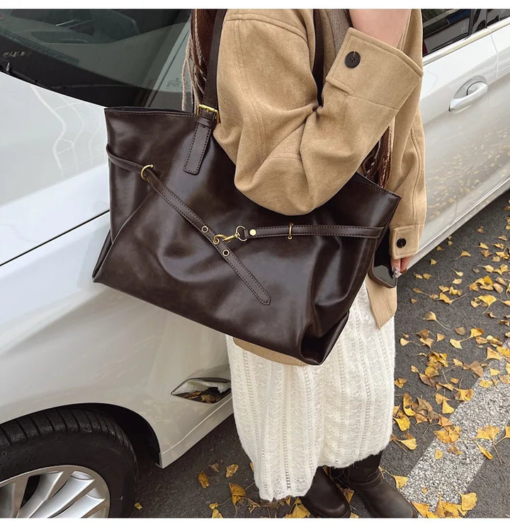 Woman carrying coffee brown leather tote bag next to car
